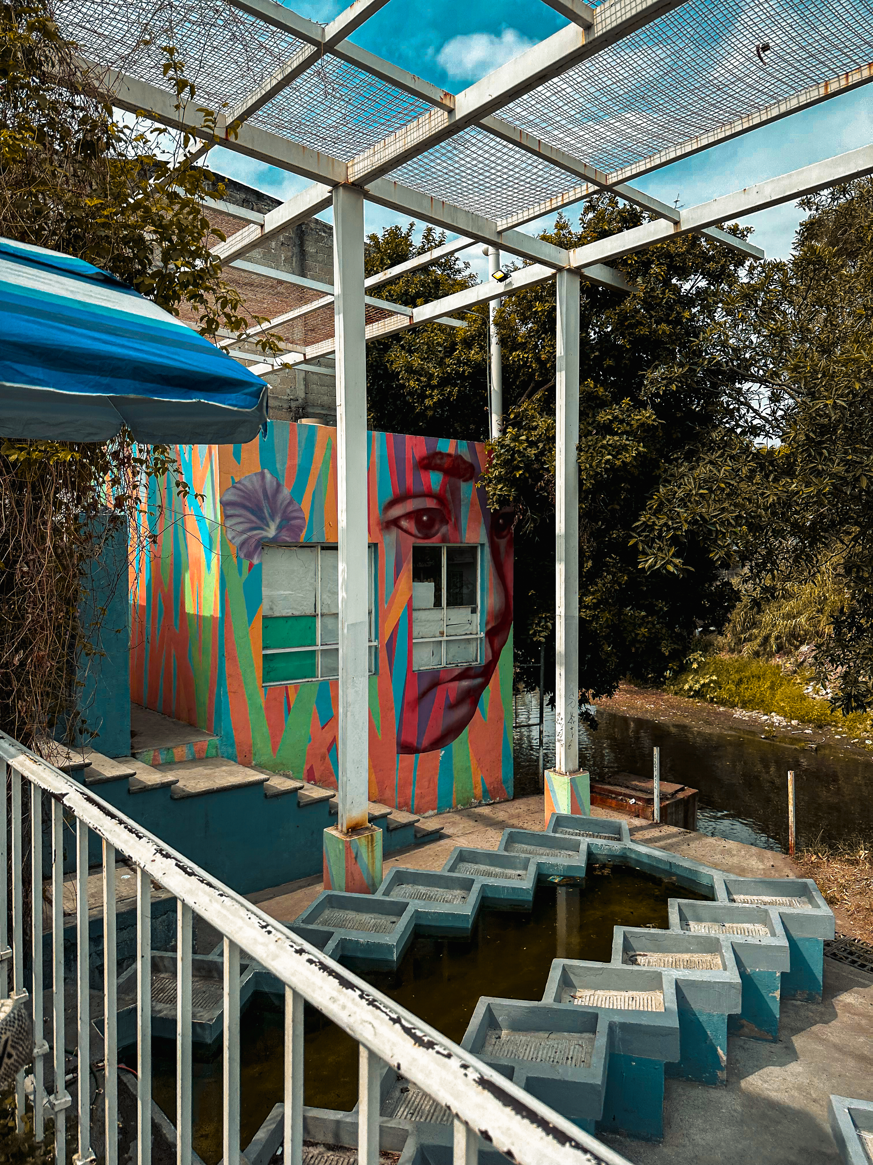 Colorful outdoor wash area with mural and water basins